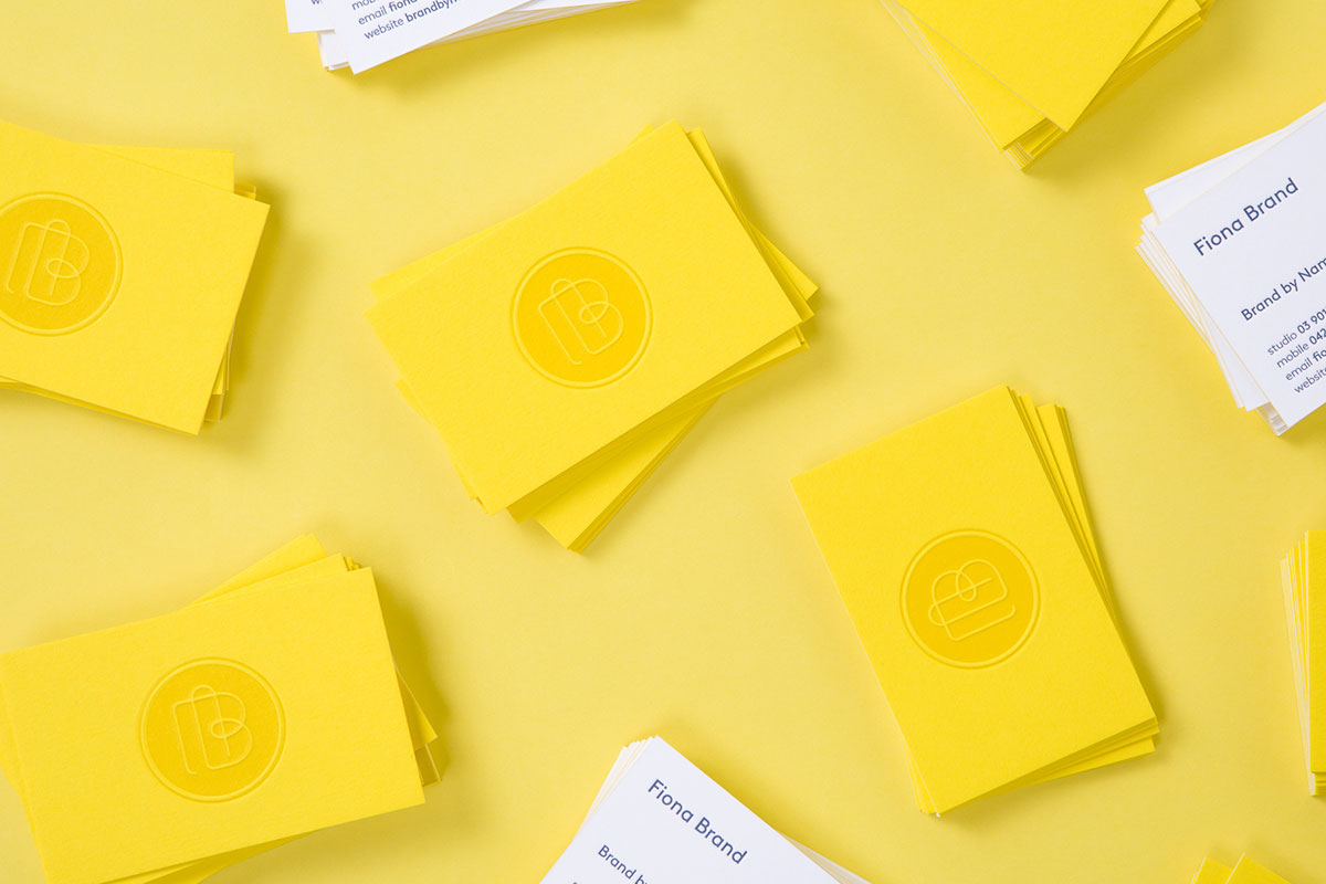 By Name’s business cards scattered on a yellow background