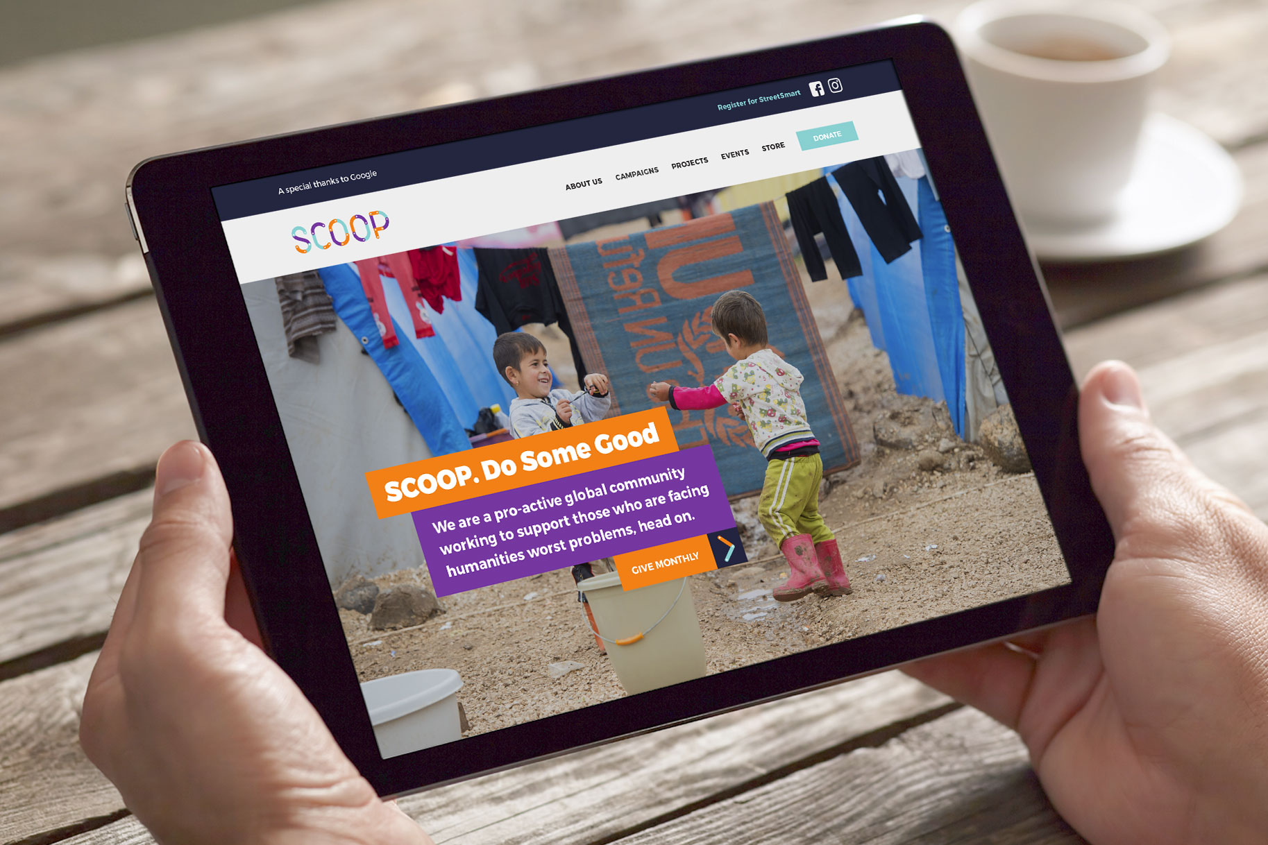 SCOOP Foundation website shown on an ipad screen, held in two hands with a cup of coffee in the background